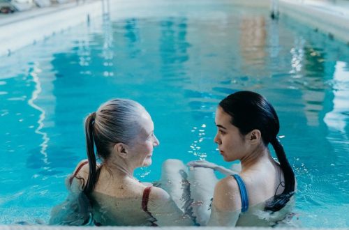 Elderly and young woman bonding in a serene indoor swimming pool environment.