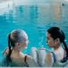 Elderly and young woman bonding in a serene indoor swimming pool environment.
